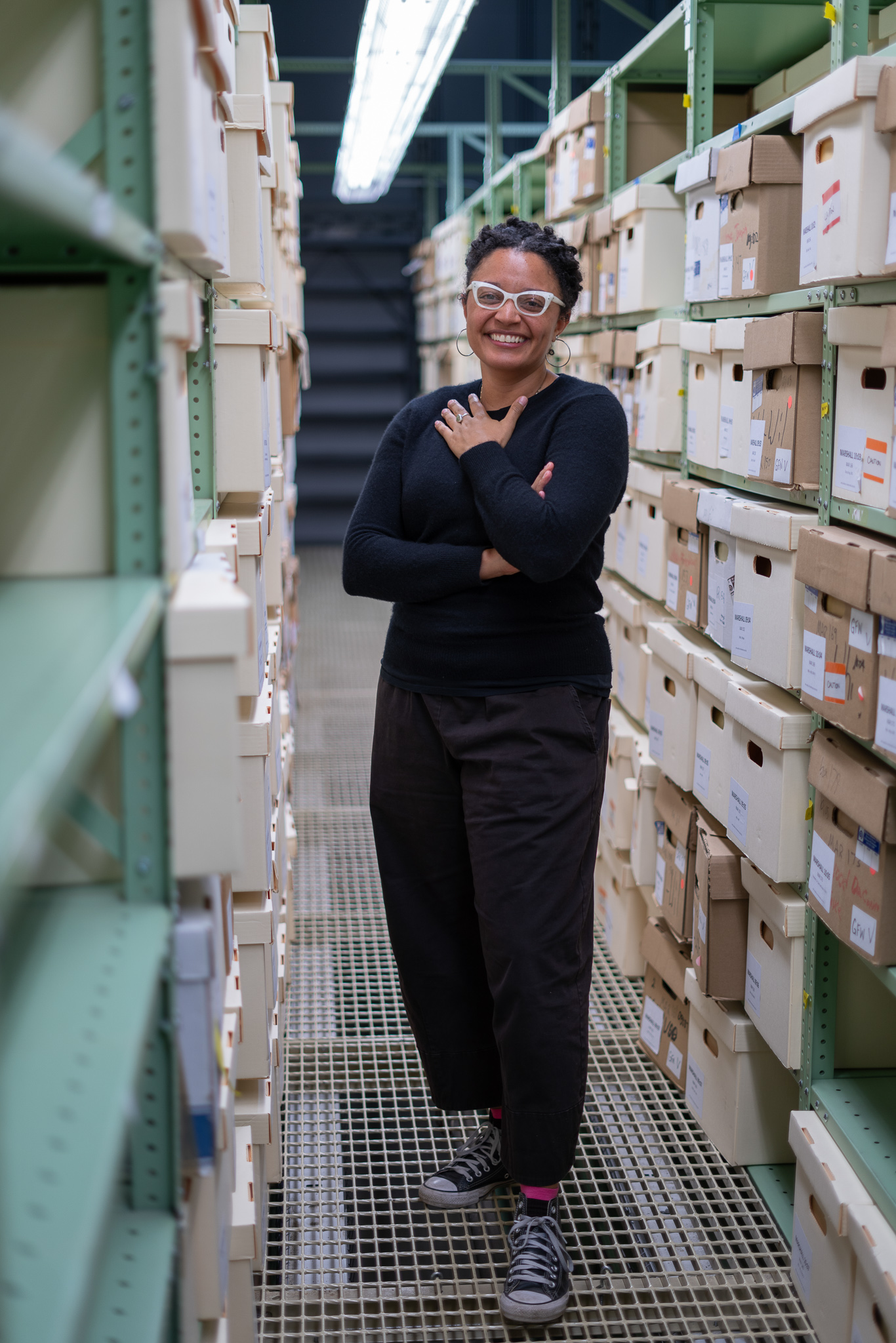 Savannah G.M. Wood standing in a hallway of archival shelving